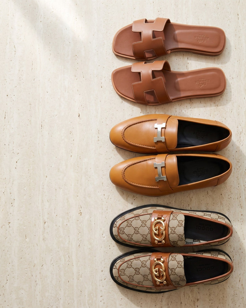 Hermès Oran sandals, Hermès Paris loafers and Gucci GG canvas loafers on travertine