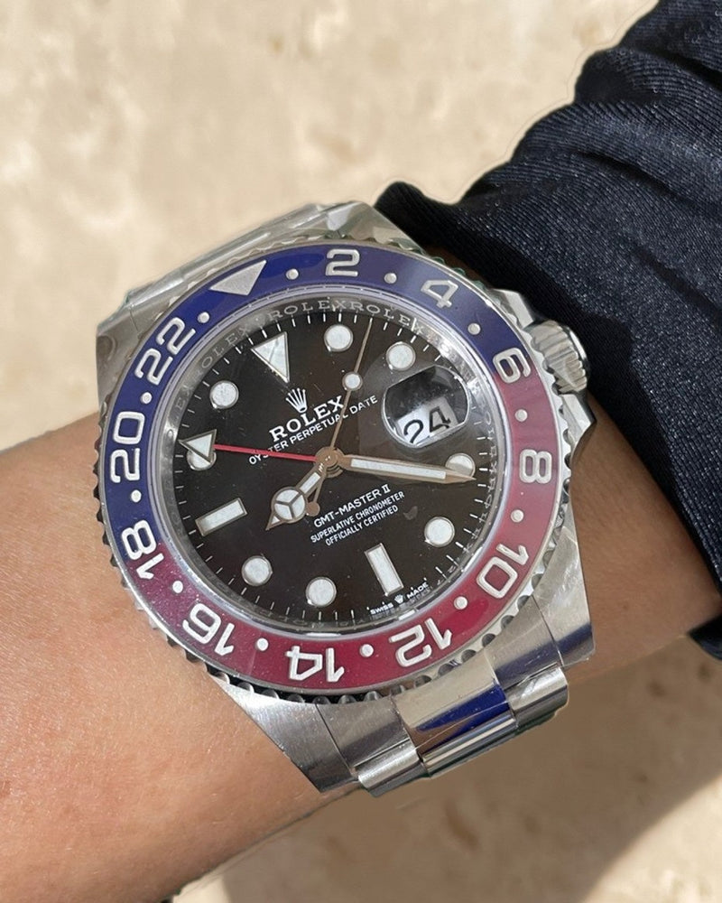 A pre-owned Rolex GMT-Master II with a blue and red bezel, worn on the wrist